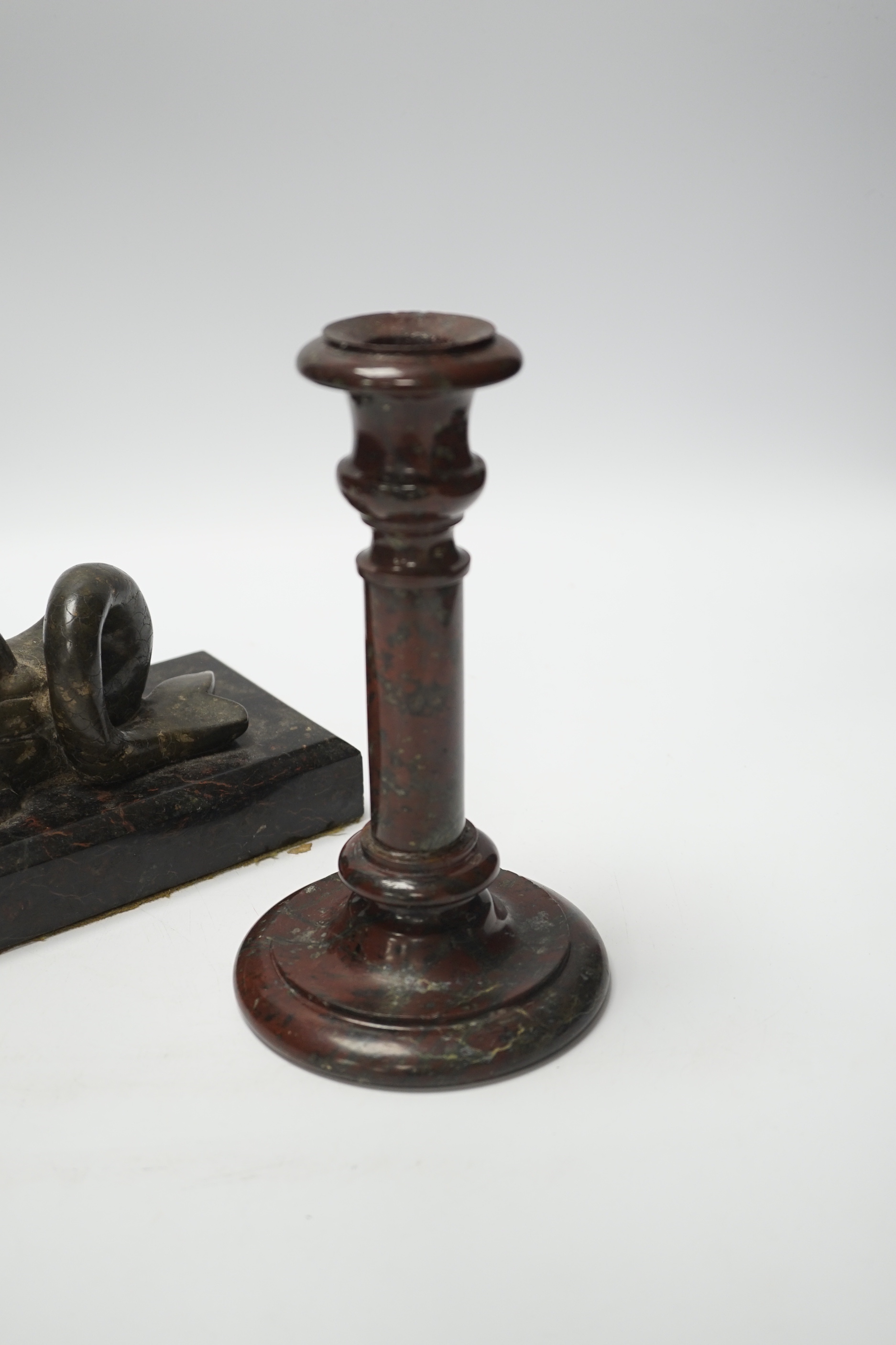 A 19th century serpentine candlestick and a carved dolphin paperweight, tallest 20cm high